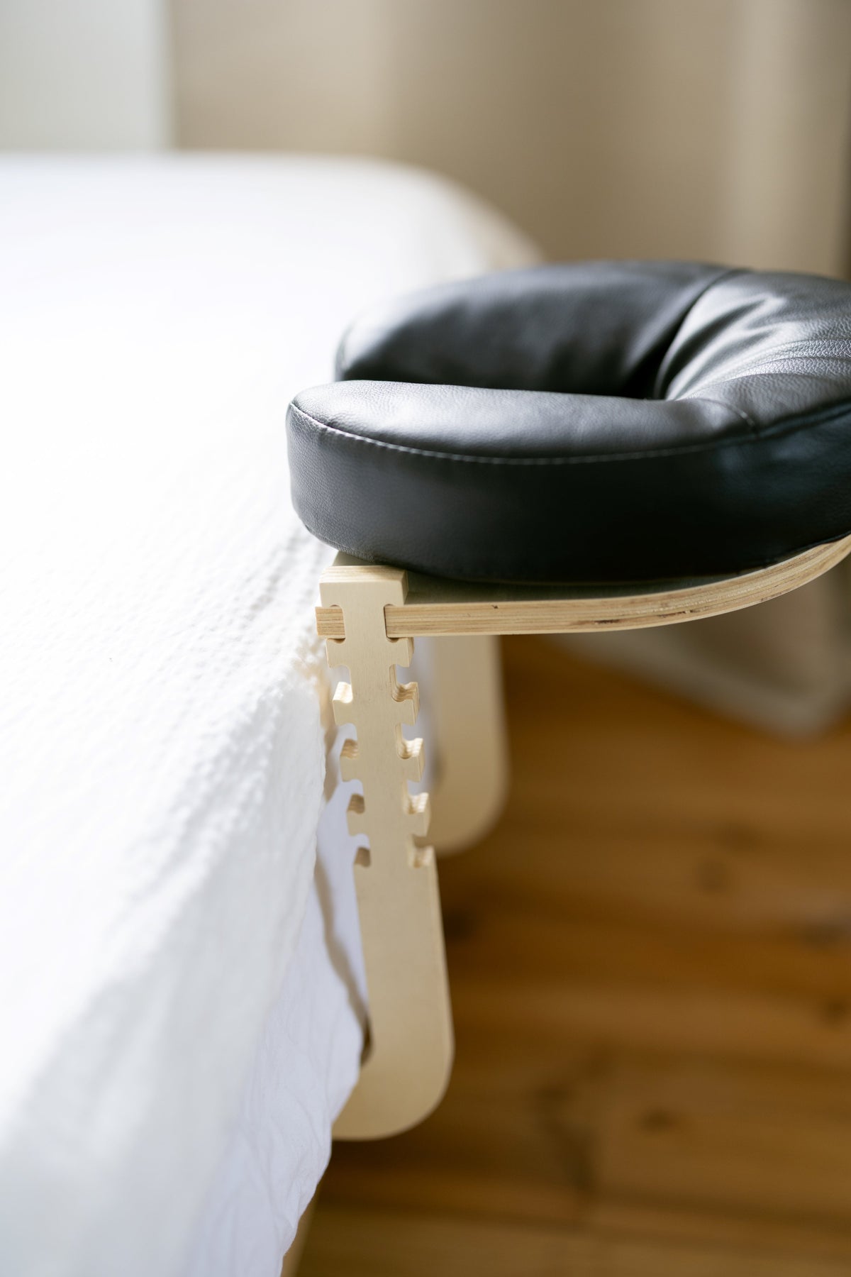 The black head cushion on the wooden frame at the edge of a made bed