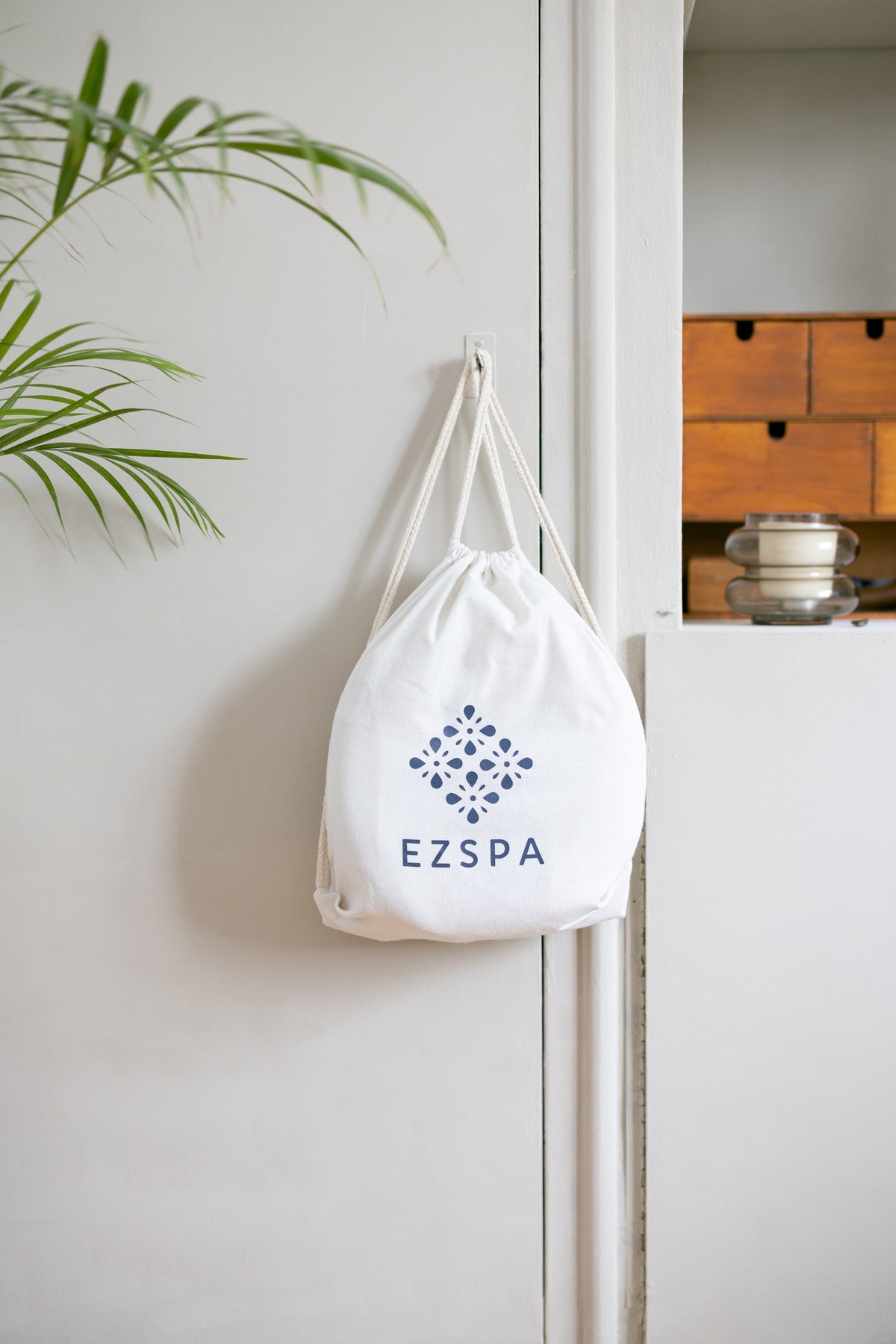 The cotton carry bag from Ezspa with the logo, hung up in a bedroom