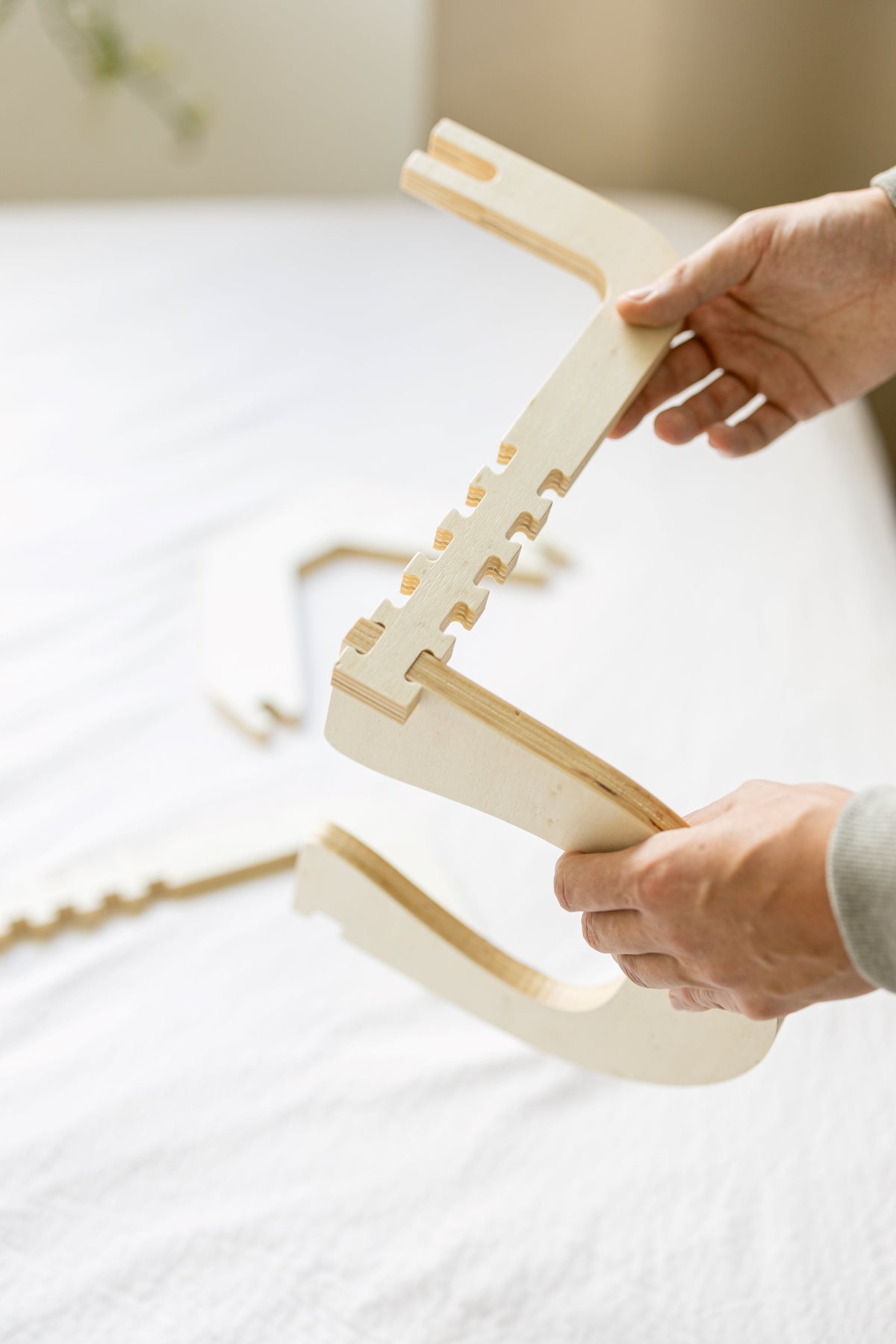 Two hands unfold the wooden frame of the Ezspa Bed Massage Set