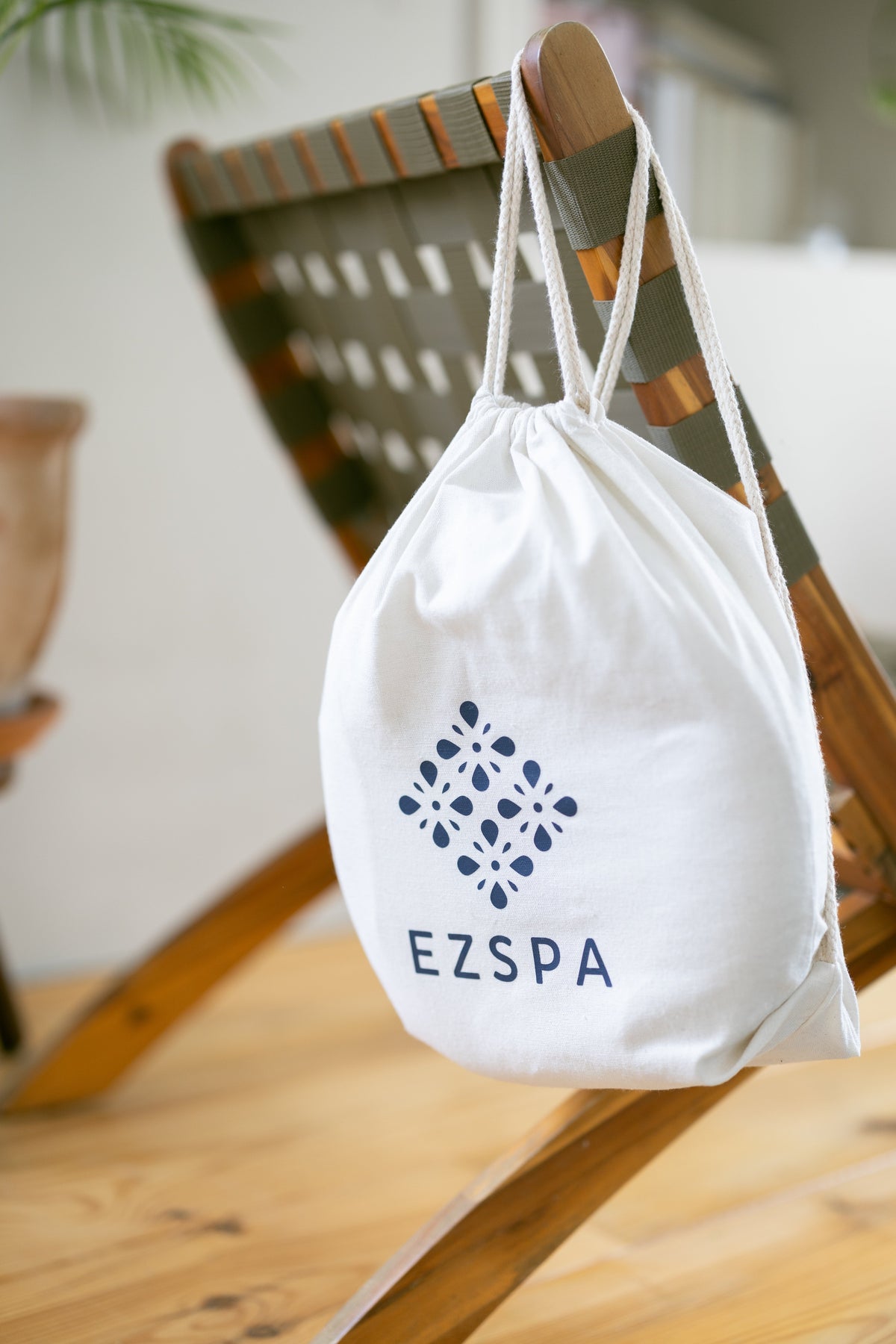 The cotton carry bag from Ezspa with the logo, hanging on a chair