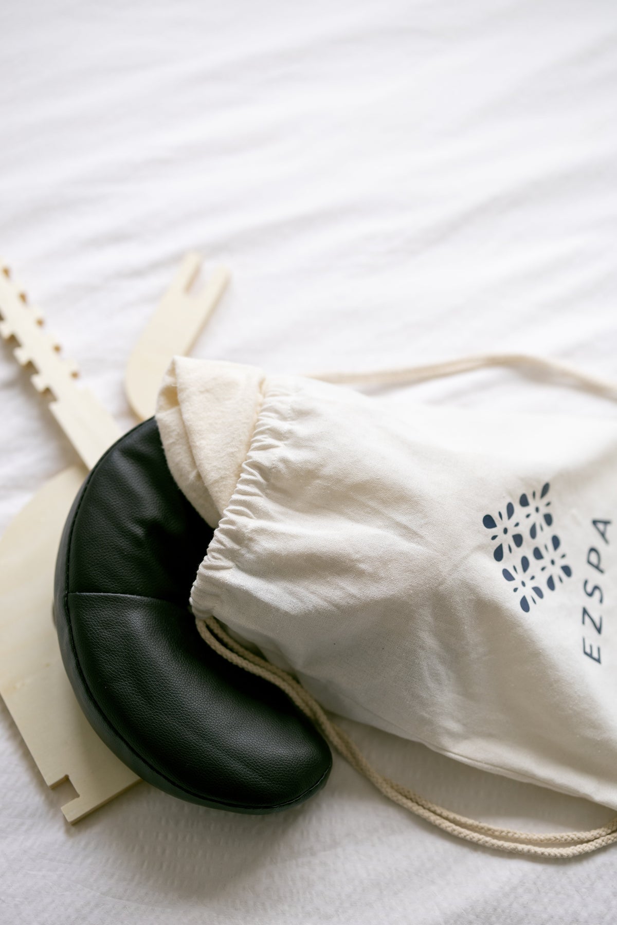 The carry bag with the black head cushion and the frame on a bed