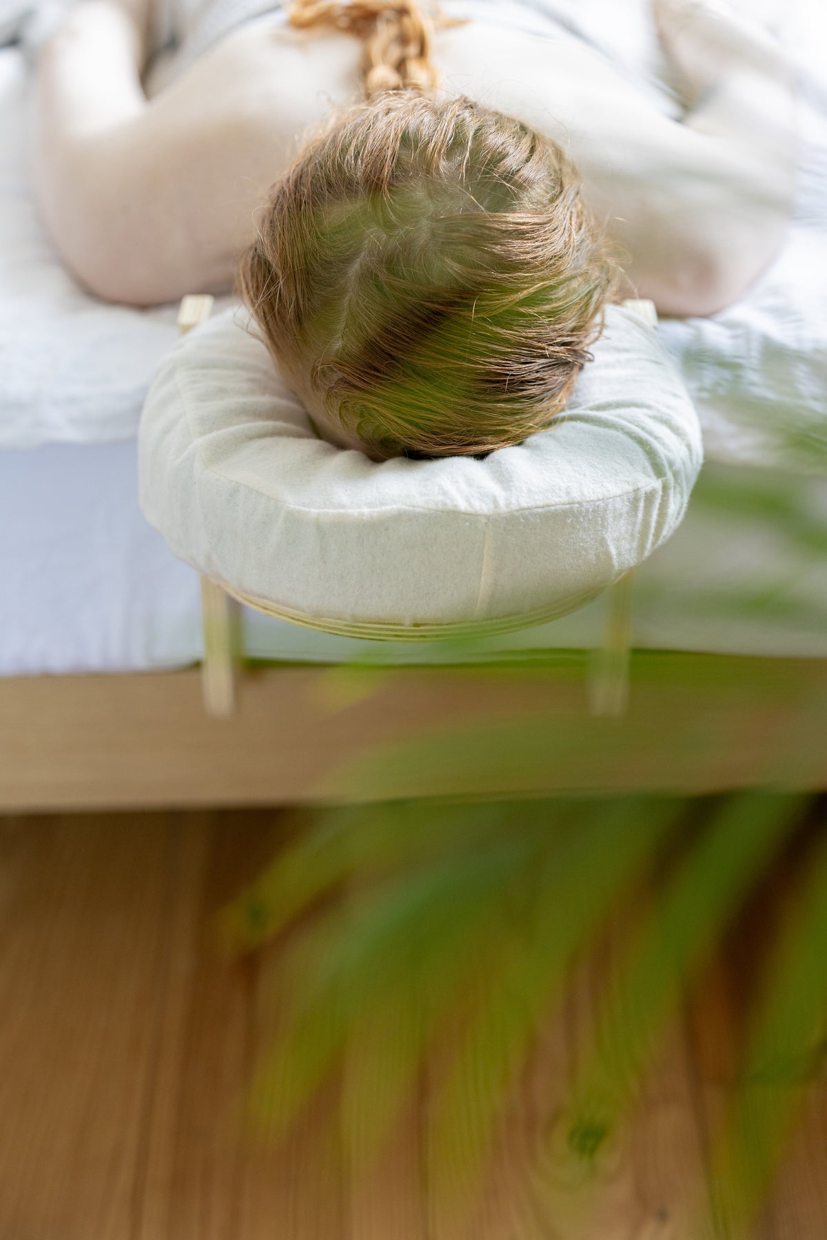 Someone lying with their head in the Ezspa headrest, with a plant in the foreground