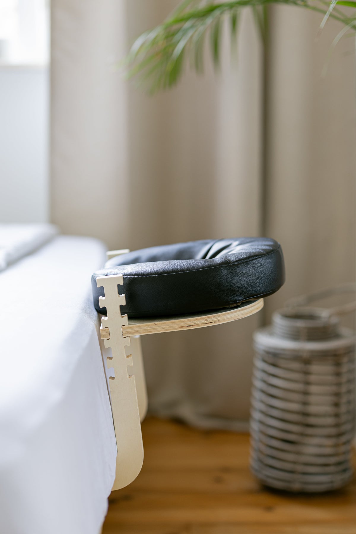 The black head cushion on the wooden frame at the foot of a bed