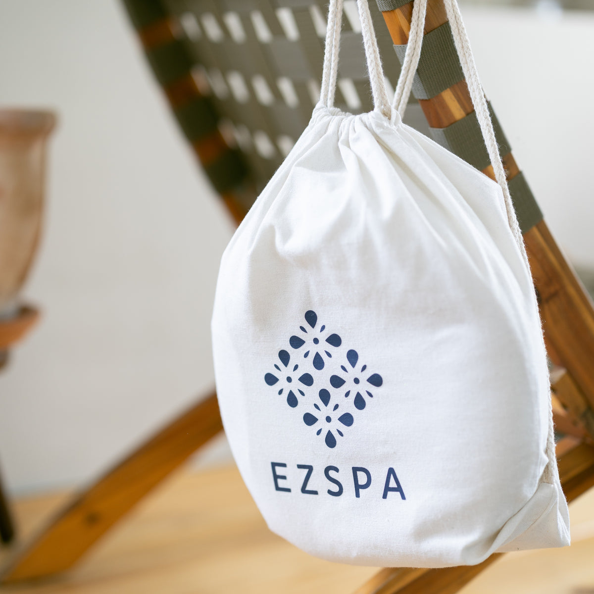 The cotton carry bag from Ezspa with the logo, hanging on a chair