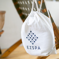 The cotton carry bag from Ezspa with the logo, hanging on a chair