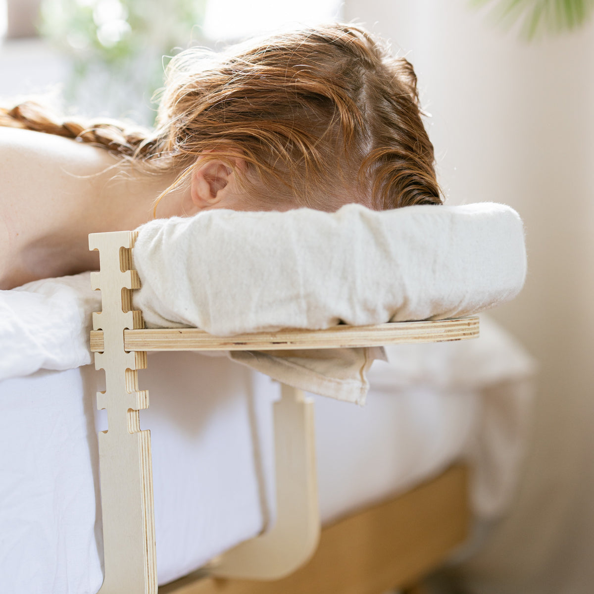 Woman lying on a bed with her face in the headrest of the Ezspa Bed Massage Set