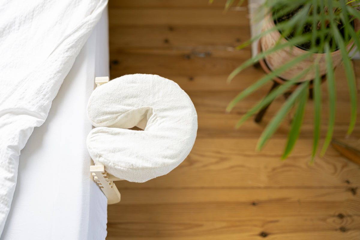 The Ezspa Bed Massage Set at the edge of a made bed, with a wooden floor below